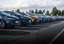 Dlouhá řada moderních automobilů Toyota různých barev, včetně nového C-HR, zaparkovaná v přesné diagonální linii na venkovním polygonu během předváděcí akce pro firemní flotily.